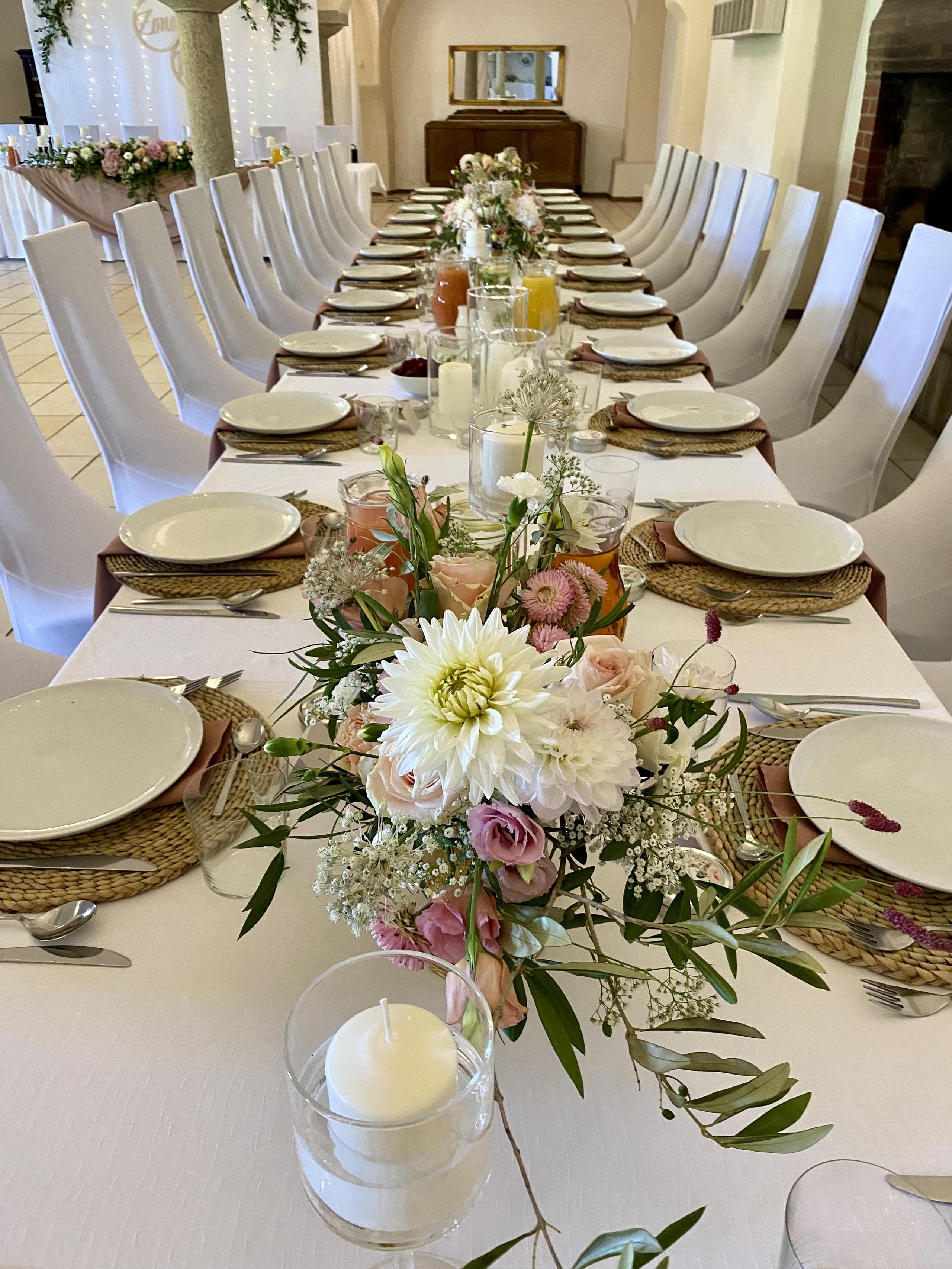 Lange Hochzeitstafel mit Blumen, Kerzen und Gedecken